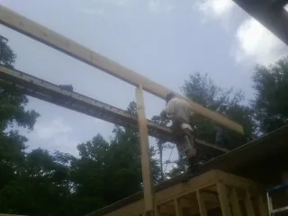 Carpenter setting a ridge beam over a new addition frame — Ice Dam Removal by Roofing Brothers in Vernon