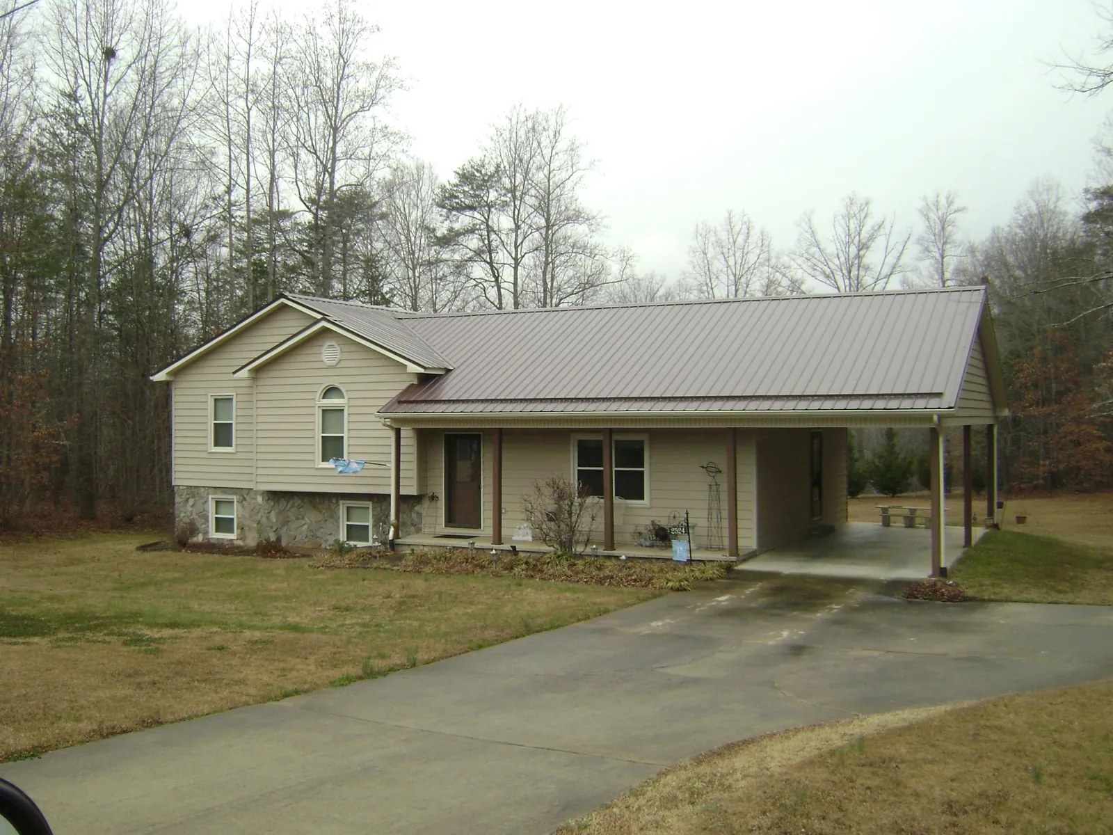 Brown metal roof on a tan split level home with an attached carport in Vernon